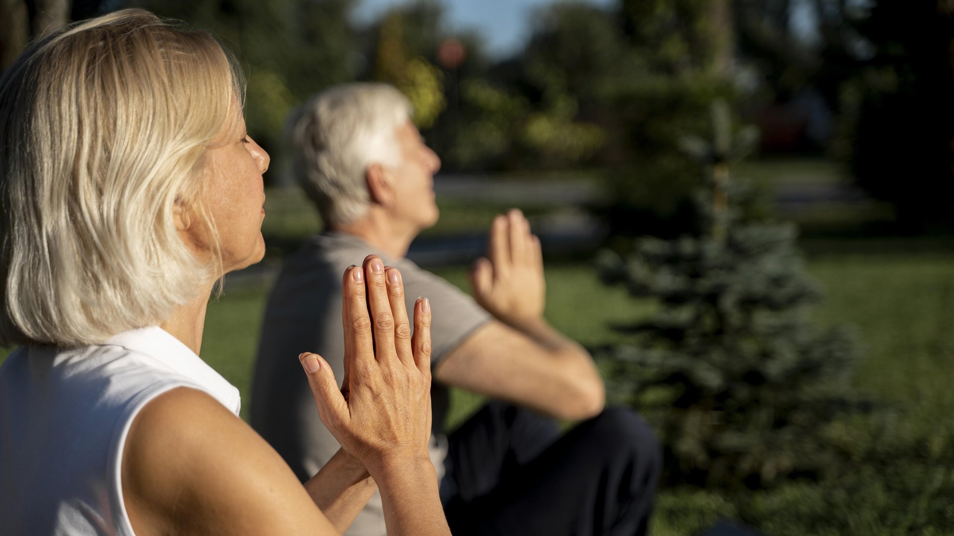 side-view-older-couple-practicing-yoga-outdoors